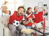 family of fans watching a football match on TV at home