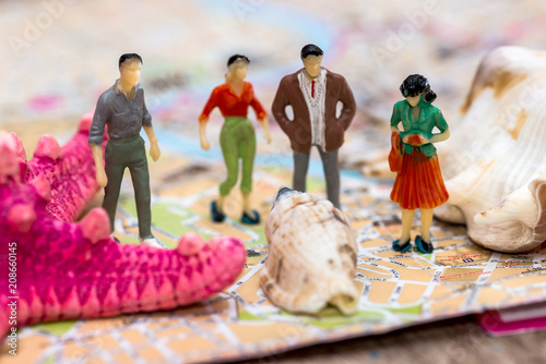 Mini man woman figures standing on city map with seashells