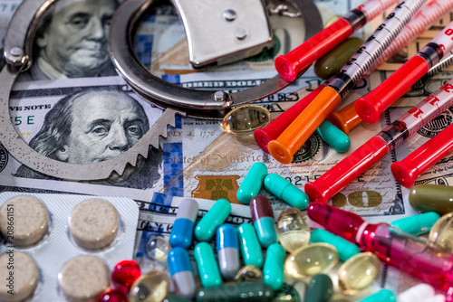 Medical concept on dollar background, pills, syringes and handcuffs