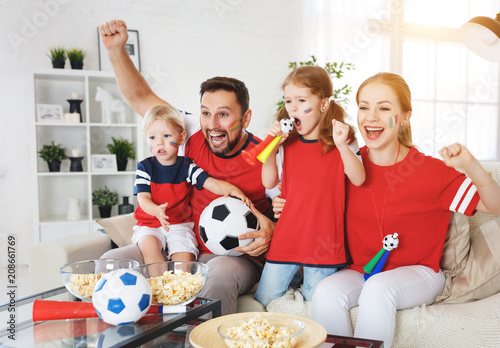 family of fans watching a football match on TV at home