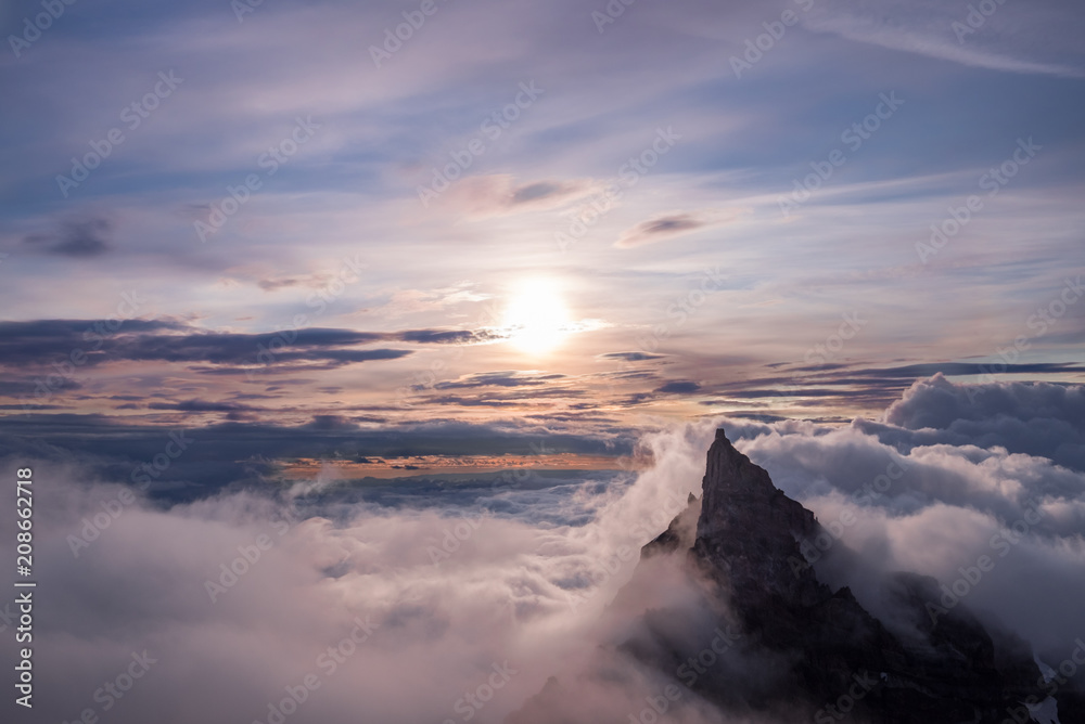 Landscape of mountain peaking over clouds, lit by sun Landscape of mountain peaking over clouds, lit by sun