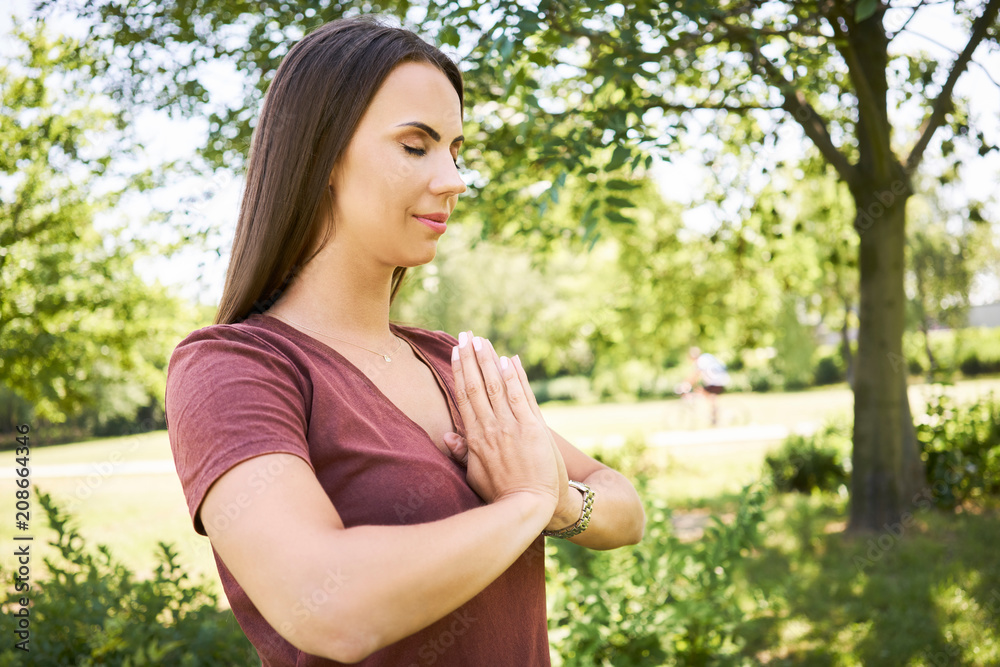 Young woman meditating outdoors in a park during summer Young woman meditating outdoors in a park during summer