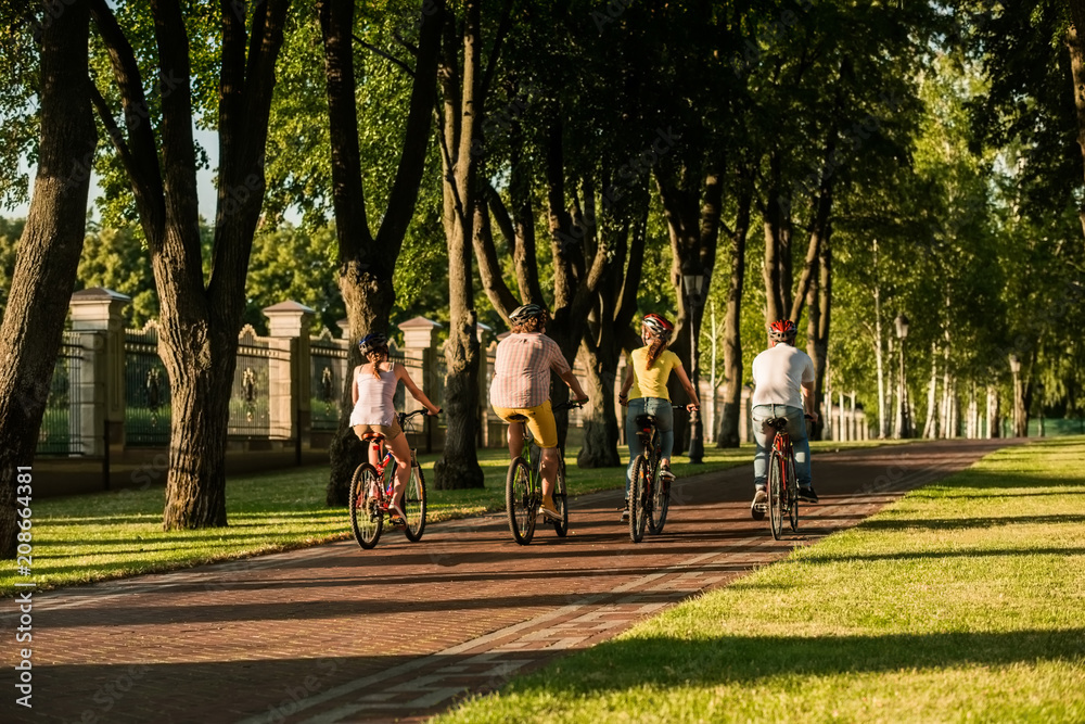 Obraz premium Active students on bikes, back view. Four friends on summer vacation. People and healthy lifestyle.