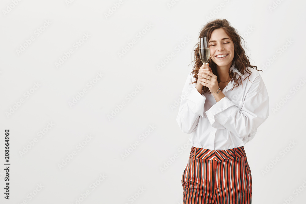 Alcohol is my best friend. Funny pleased and relaxed woman with curly hair in stylish blouse and striped pants, holding glass of champagne near face, leaning at drink, smiling with closed eyes Alcohol is my best friend. Funny pleased and relaxed woman with curly hair in stylish blouse and striped pants, holding glass of champagne near face, leaning at drink, smiling with closed eyes