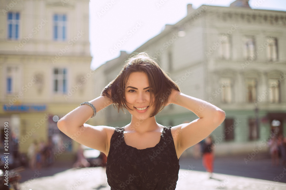 Lifestyle portrait of cheerful brunette woman wearing trendy dress, walking on the city streets