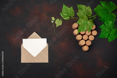 Gape bunch of cork with leaves, envelope and letter on rusty background.