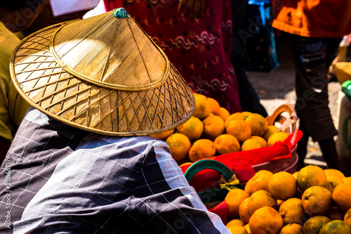 Burmese selling orange in a street market wearing typical asian conical hat, Yangon, Myanmar
