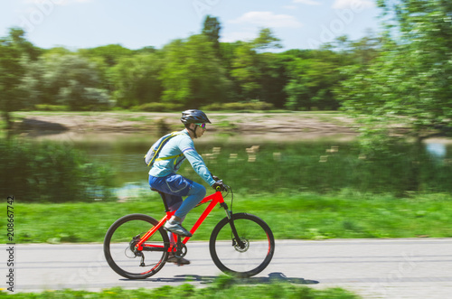 A cyclist in a helmet rides a bicycle path  motion blur