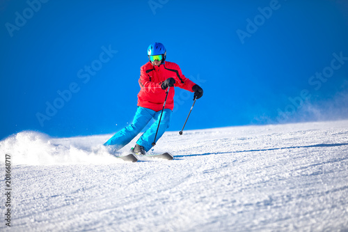Człowiek na nartach na przygotowanym stoku ze świeżym, nowym śniegiem.