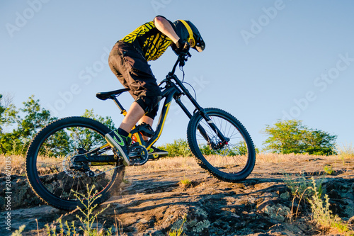 Cyclist Riding the Mountain Bike on the Summer Rocky Trail at the Evening. Extreme Sport and Enduro Cycling Concept.