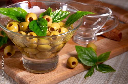 Green pitted olives in a glass cup