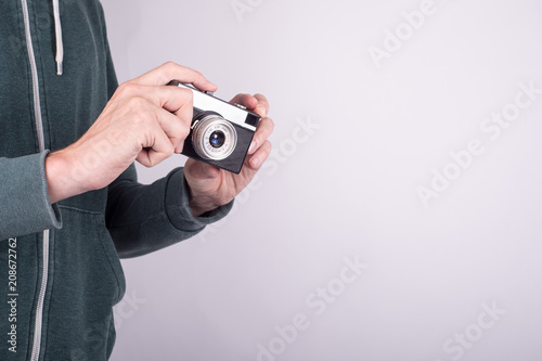 Female hands holding retro photo camera on the gray wall background