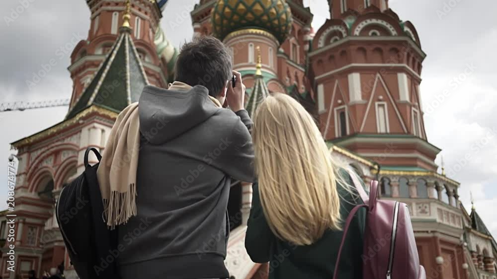 Rear view of a young couple taking pictures of Moscow Saint Basil's Cathedral, Russia. Concept of tourism. Handheld medium shot Rear view of a young couple taking pictures of Moscow Saint Basil's Cathedral, Russia. Concept of tourism. Handheld medium shot