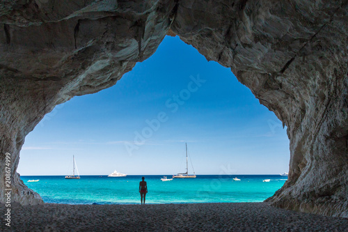 Fototapeta Woman inside a cave at Cala Luna beach