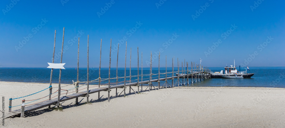 Panorama of a jetty and ferry in the blue water of the Wadden sea, The Netherlands