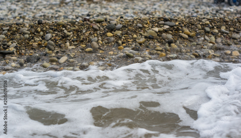 pebble stones on the sea beach, the rolling waves of the sea with foam pebble stones on the sea beach, the rolling waves of the sea with foam