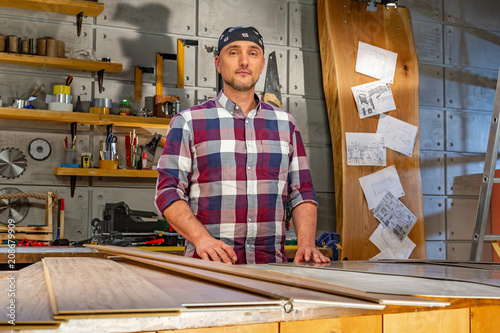 Carpenter doing his job in carpentry workshop. a man in a carpentry workshop measures and cuts laminate © Georgii