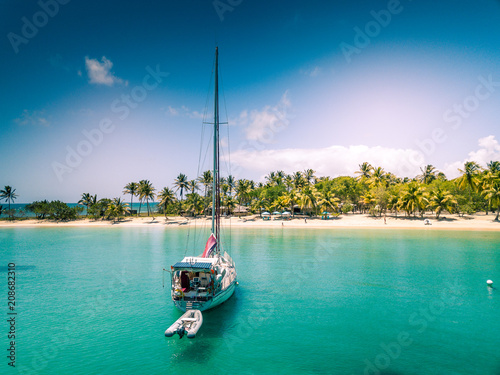 isolated sailboat anchoring in front of a white sand beach on Caribbean island - Mayreau - St Vincent and the Grenadines photo