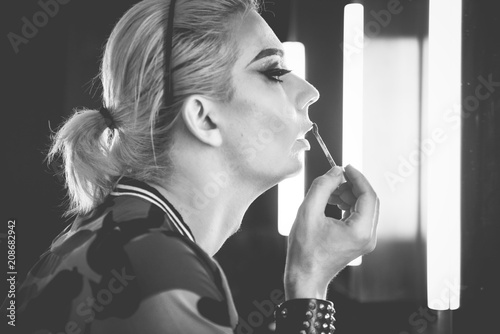 Drag queen applying lipstick on her lips