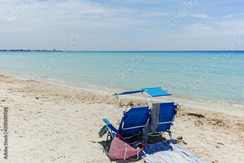 Beach equipment  chairs on white sandy beach with light blue sea water  beach vacation concept