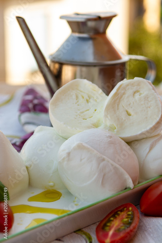 Fresh soft Italian white cheese mozzarella buffalo, original from Campania, Paestrum and Foggia regions, South Italy, served with tomatoes and fresh basil