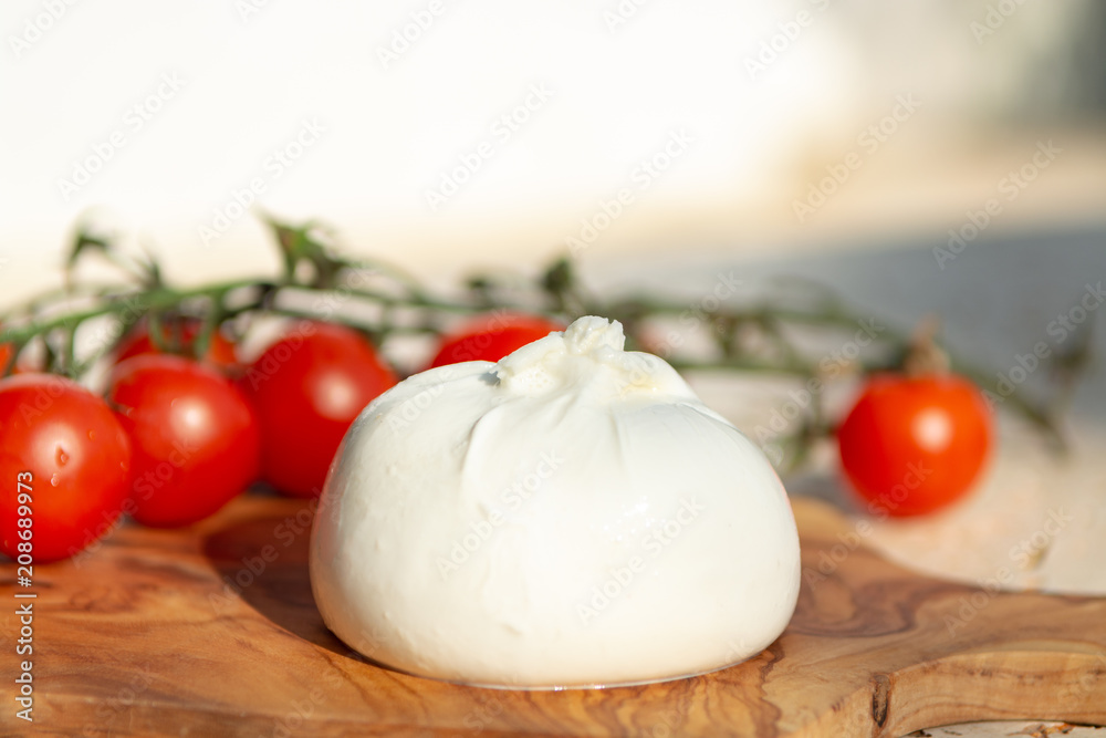 Fresh soft white burrata, buttery cheese, made from a mix of mozzarella and cream, original from Apulia region, Italy with tomatoes