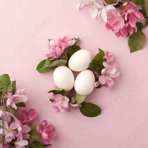 Easter eggs and pink flowers on white background. Easter nest. Flat lay  top view  concept of spring  femininity and beauty.