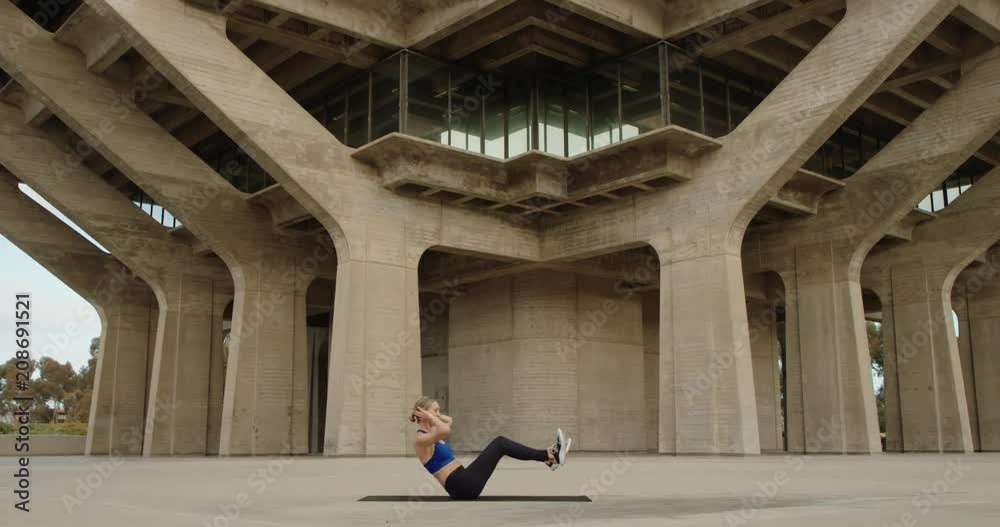 Athletic fit woman exercising doing ab exercises outside in city working out 