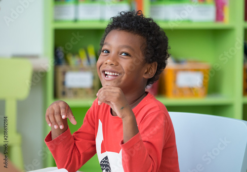 African American ethnicity kid smiling at library in kindergarten preschool classroom.happy emotion.education concept. photo