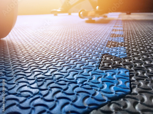 The blue rubber gym floor with the shadow of dumbell behind.