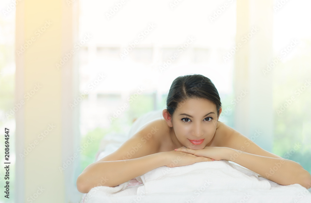 Spa treatment for good health.Beautiful woman lying and relaxing on massage bed.Woman having wellness body massage and feeling visibly good at spa salon Spa treatment for good health.Beautiful woman lying and relaxing on massage bed.Woman having wellness body massage and feeling visibly good at spa salon