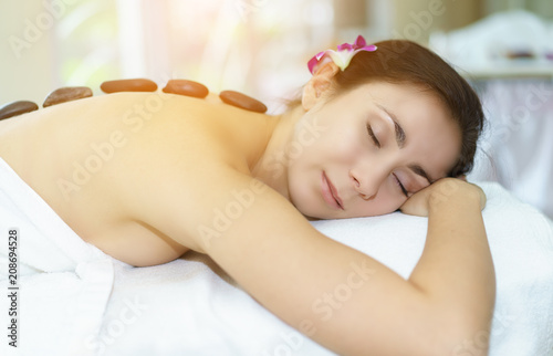 Spa treatment for good health.Beautiful woman lying and relaxing on massage bed.Woman having wellness body massage and feeling visibly good at spa salon