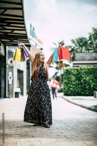Portrait of young happy smiling woman with shopping bags walking in street © Johnstocker