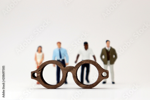 The concept of biased views judged by appearances. Various miniature people standing behind the glasses. photo