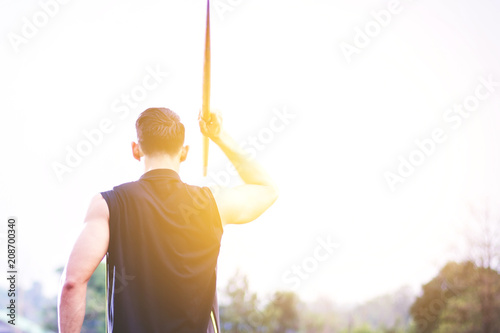 sportsman warming up and practicing javelin throw in yard photo