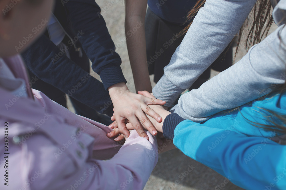 A group of teenagers have many hands connected. The concept of teamwork and unity. A group of teenagers have many hands connected. The concept of teamwork and unity.