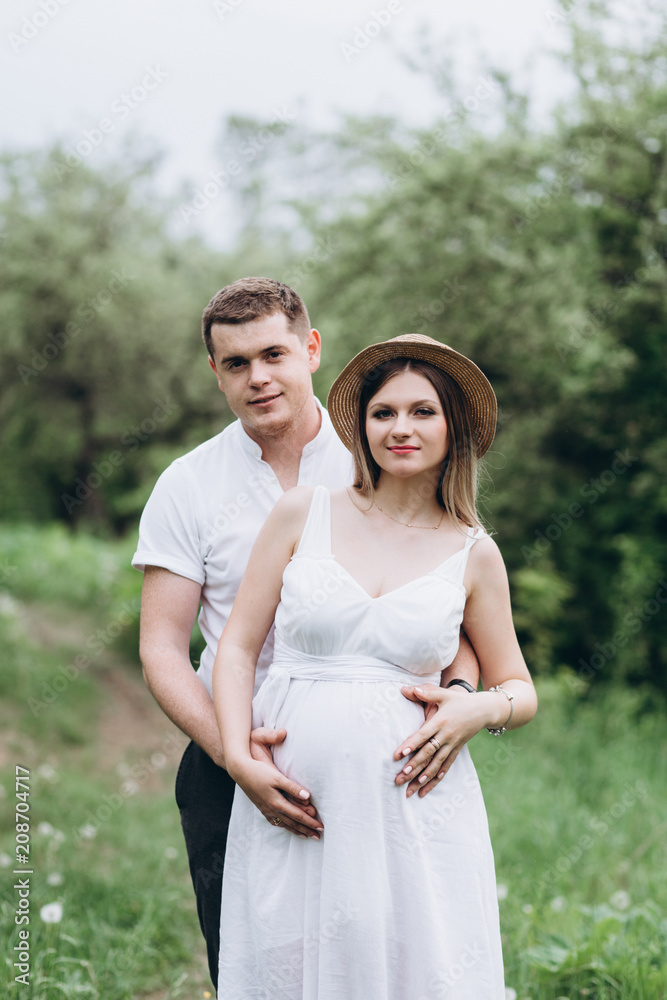 The lovely couple in love embracing and standing on the grass The lovely couple in love embracing and standing on the grass