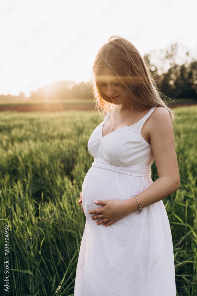 The pregnant girl stands on the fiield The pregnant girl stands on the fiield