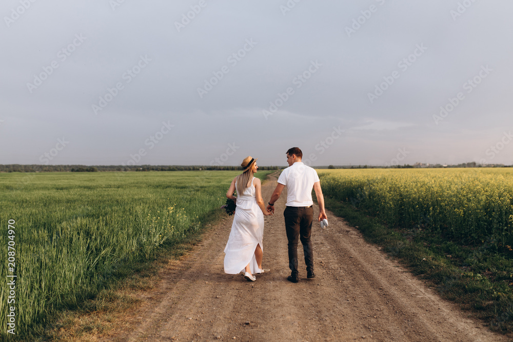 The lovely couple in love walking along field The lovely couple in love walking along field
