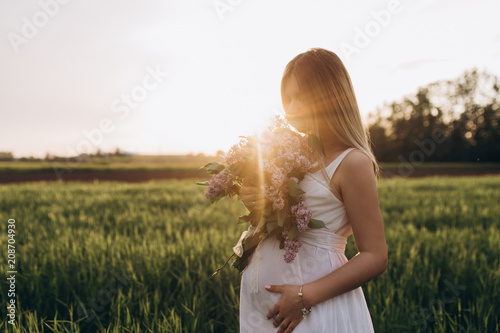 The pregnant girl stands on the fiield