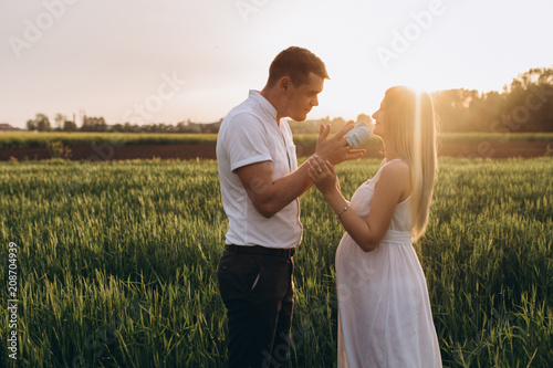 The wife and husband  keeping babyish shoes and standing on the field