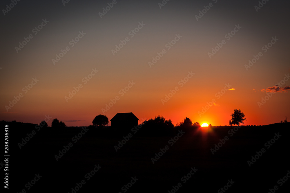A picturesque sunset with a barn's silhouette