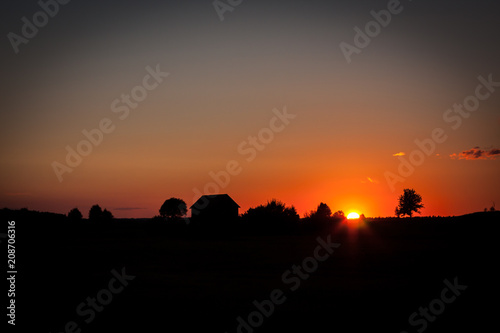 A picturesque sunset with a barn's silhouette
