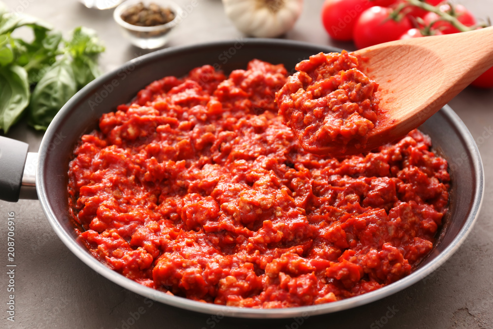 Wooden spoon with meat sauce over frying pan on table Wooden spoon with meat sauce over frying pan on table