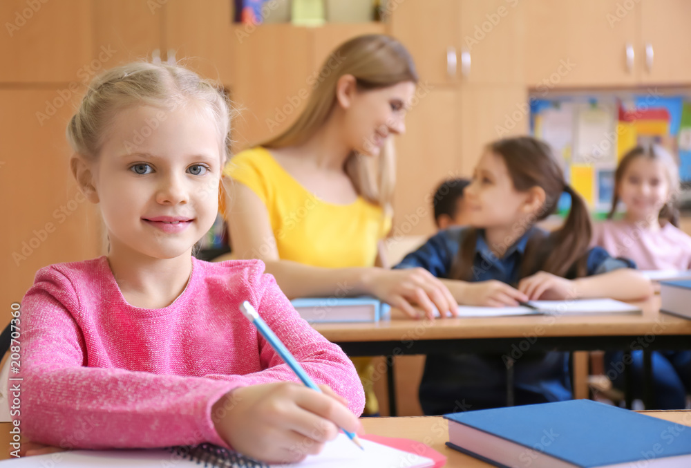 Cute girl doing homework in classroom at school Cute girl doing homework in classroom at school