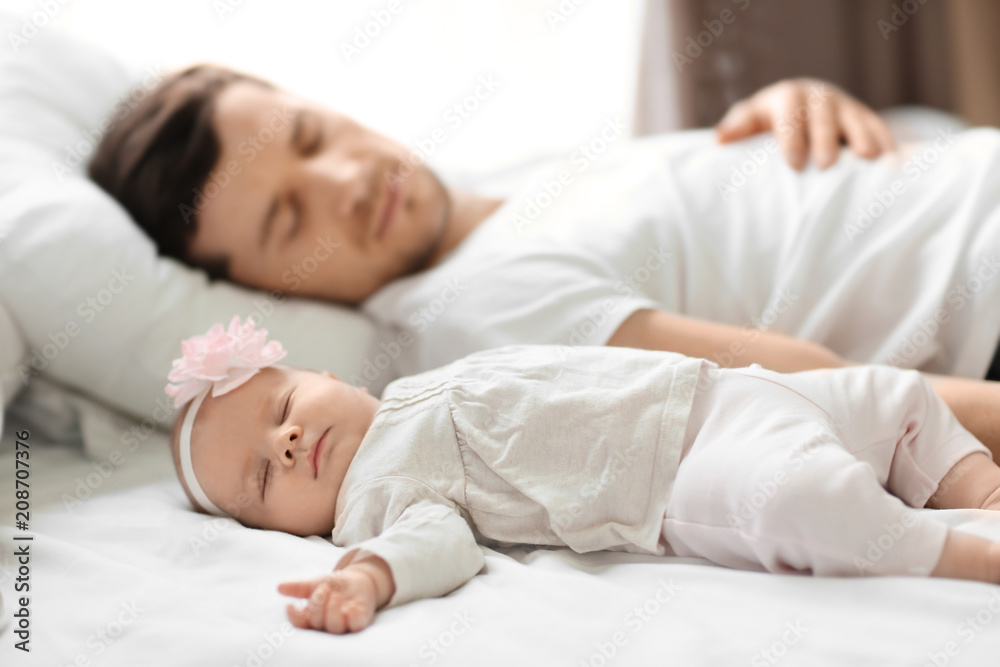 Young father with cute baby sleeping on bed at home Young father with cute baby sleeping on bed at home