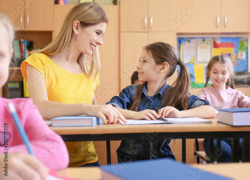 Female teacher helping girl with her homework in classroom at school