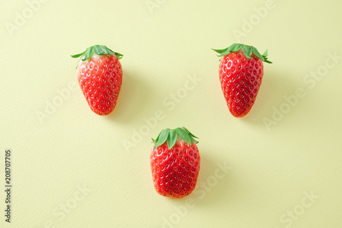 Tree strawberry fruits on yellow background.