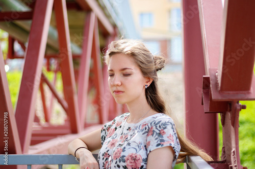 Portrait of a girl on the bridge. Construction of the bridge in the background