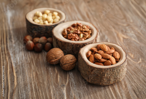 Photos Bowls with various tasty nuts on wooden table
